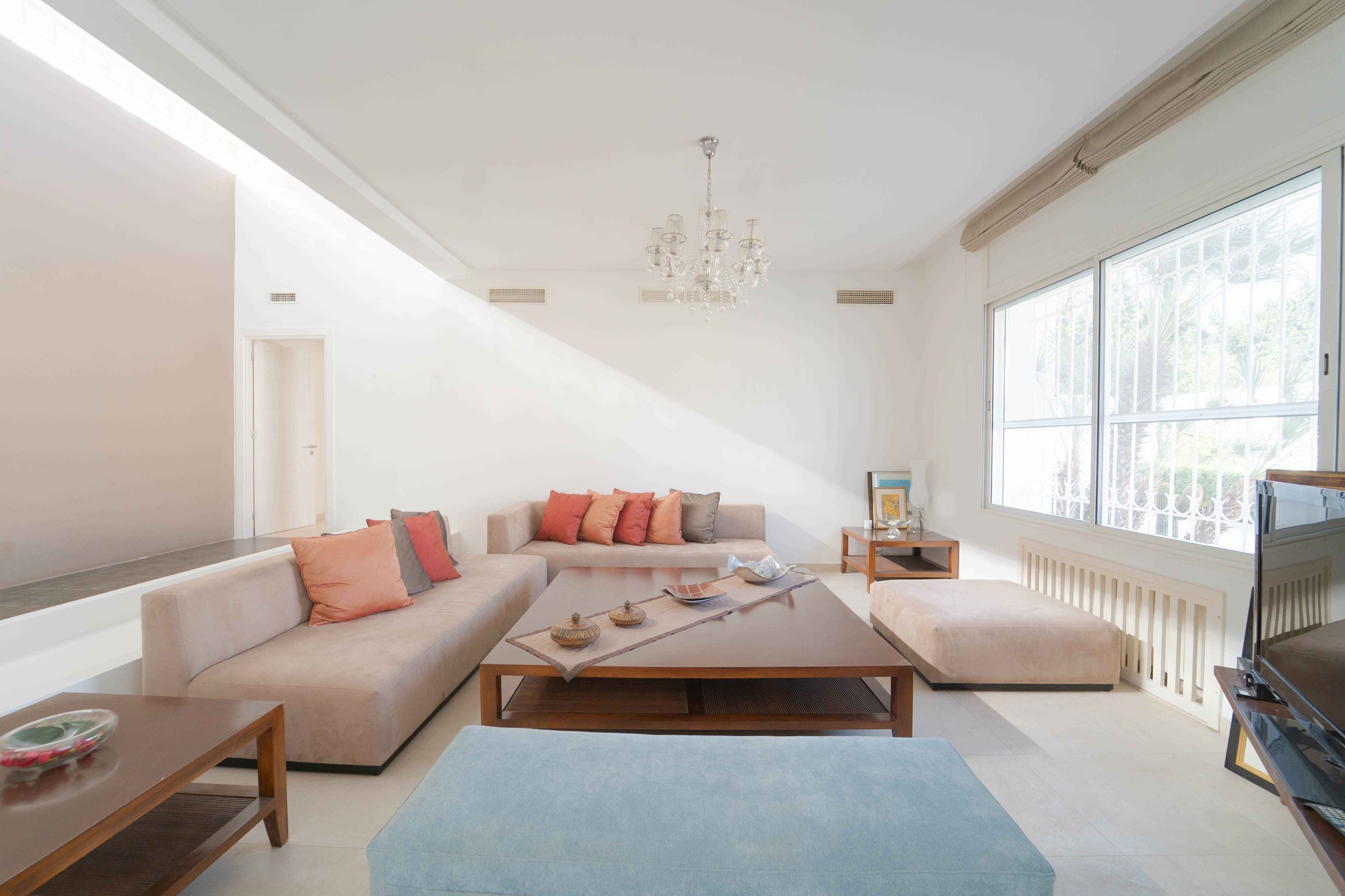 A modern living room with a sofa, coffee table, ottoman, and a television.