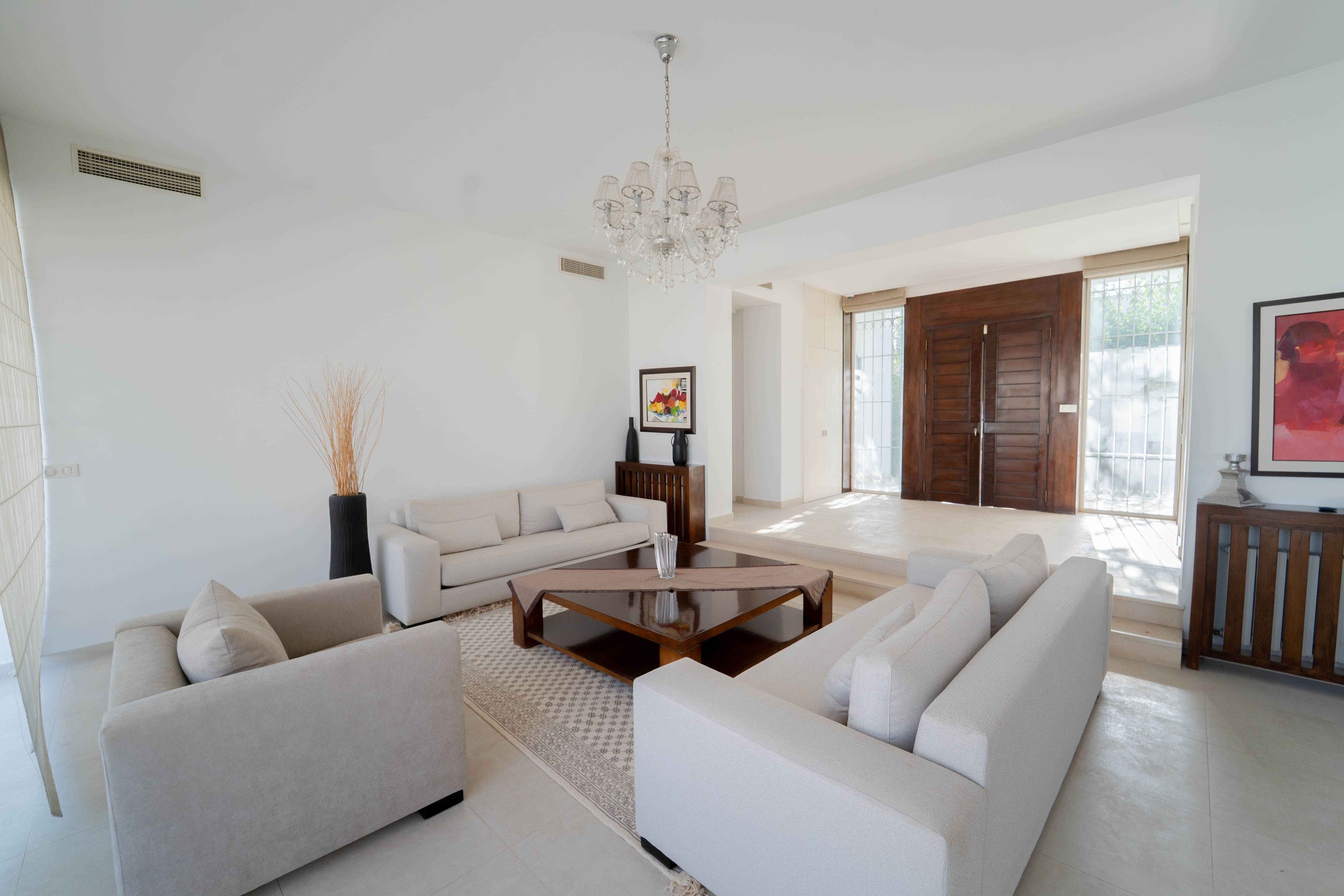 A modern living room with a sofa set, a coffee table, and a chandelier.