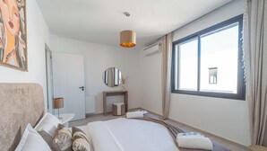 A hotel room with a bed, bedside table, lamp, mirror, and a large window. - New 2BR Apt Parking Netflix La Marsa (La Marsa)