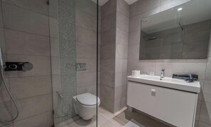 Ein modernes Badezimmer mit einer Duschkabine aus Glas, einer Toilette und einem weißen Waschtisch mit Spiegel.