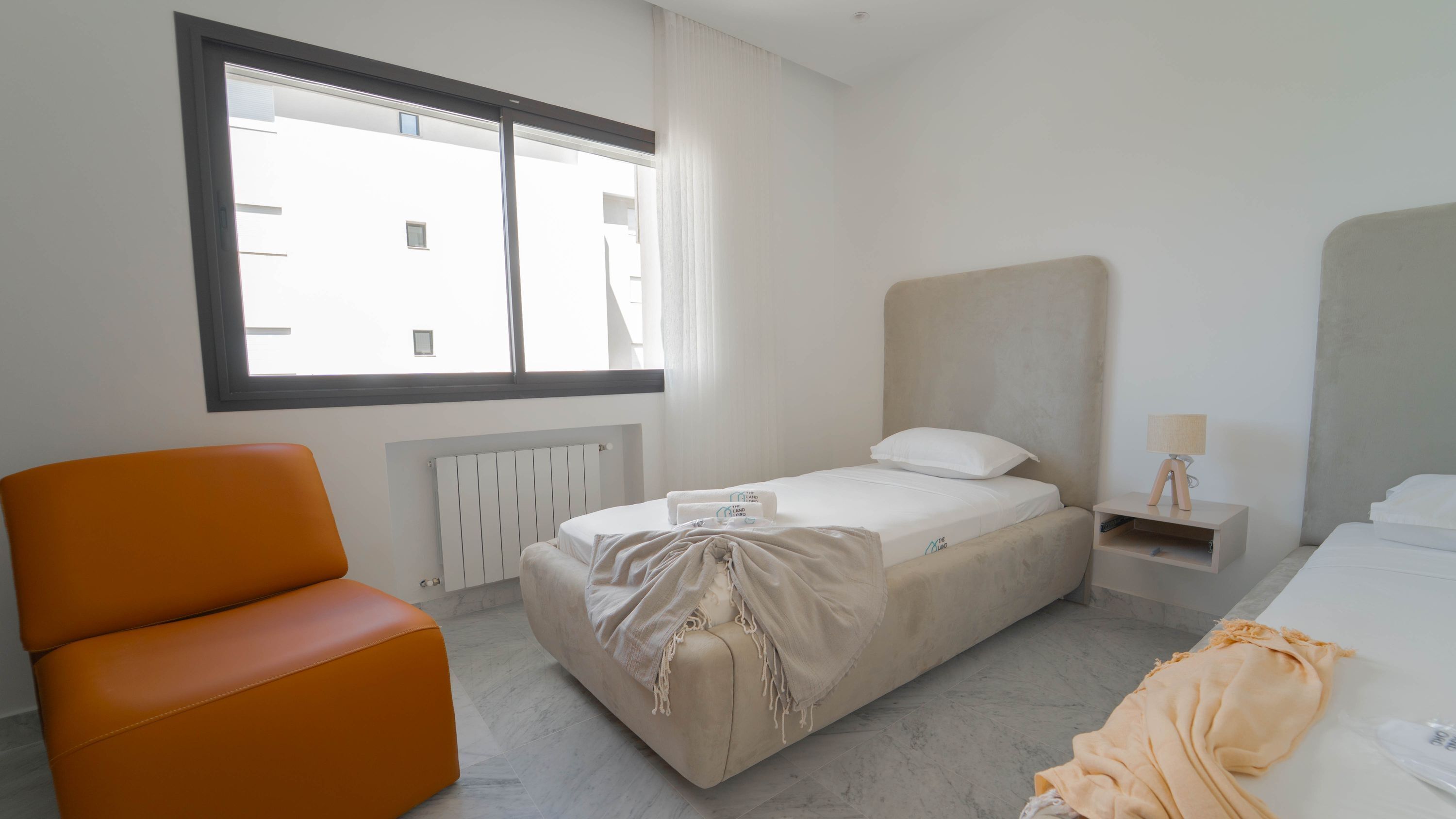 Una habitación de hotel con cama, una silla, una mesita de noche y una ventana.