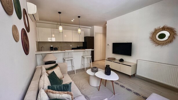 A modern living room with a sofa, a coffee table, and a TV. - Chic Boho 1BR Modern Comfort (La Marsa)