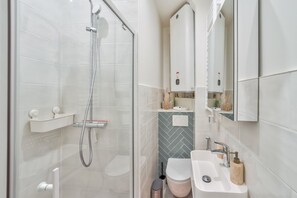 Ein modernes Badezimmer mit einer gläsernen Duschkabine, einem weißen Waschbecken und einer Wandverkleidung aus Ziegelmusterfliesen.