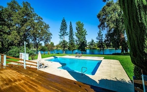 Una piscina con muelle de madera, una mesa pequeña y dos sillas.