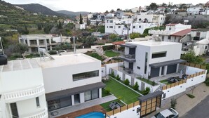 Un edifici residencial modern amb una piscina al terrat, un patio cobert i vista a una ciutat amb turons.