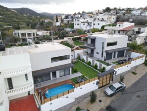 A modern residential building with a rooftop swimming pool, a covered patio, and a view of a hilly town. - Villa Elena - Peris, Elena Villa (Gouves)