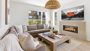 Una sala de estar moderna con un sofá, una mesa de centro, chimenea y un televisor grande.