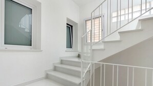 Una escalera blanca con barandilla, una ventana y una puerta.