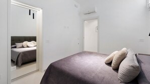 Un dormitorio moderno con una cama, un espejo y una puerta.