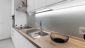 A modern kitchen with a stainless steel sink, wooden countertop, and a black wire basket. - Apartment 'Palazzo Tilde - 1 B' with Sea View, Wi-Fi and Air Conditioning (Marsala)