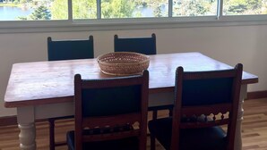 Un coin repas avec une table et des chaises, une fenêtre donnant sur un paysage vallonné et un plancher en bois.