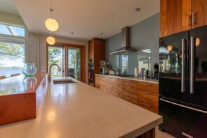 A modern kitchen with a large island, stainless steel appliances, and a view of the outdoors.
