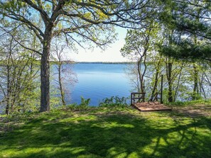 A lakeside view with a wooden deck and a bench.