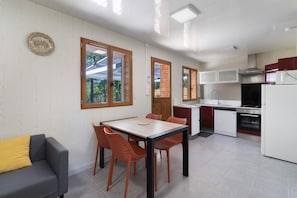 A compact kitchen with a dining area, a sofa, and a view through the windows.