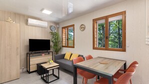 Een moderne woonkamer met een televisie, bank, eettafel en stoelen.