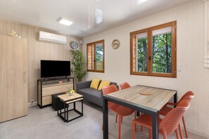 A modern living room with a TV, sofa, dining table, and chairs.