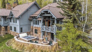A two-story house with a stone foundation, a deck, and a hot tub. - Buckhorn Townhome 264 - 5 Bedroom (Beaver Creek)