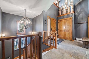 A staircase with wooden railings, a chandelier, and a door with a coat rack. - Buckhorn Townhome 264 - 5 Bedroom (Beaver Creek)