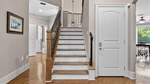 Una escalera de madera con barandilla de metal que conduce a una puerta blanca.