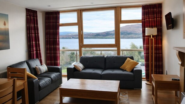 A living room with a sofa, a wooden coffee table, and a TV.