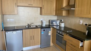 A kitchen with wooden cabinets, a stainless steel sink, a dishwasher, a toaster, and an oven.