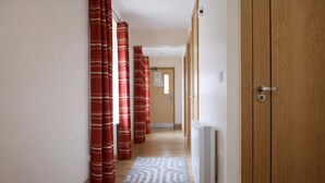 A hallway with a wooden door, red curtains, and a patterned rug.