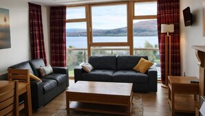 A living room with a sofa, a coffee table, and a view of a lake.