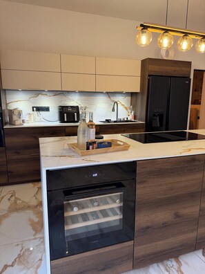 Eine moderne Küche mit Marmorarbeitsplatte, integrierten Geräten und einem Holzkorpus.