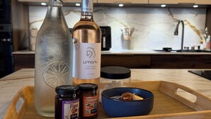 Een aanrecht met een glazen fles, een metalen fles, potten en een blauwe kom op een houten dienblad.