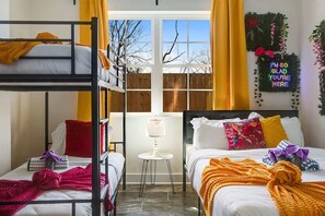 Ein Schlafsaalzimmer mit Etagenbetten, einem kleinen Tisch und einem Fenster mit Vorhängen.