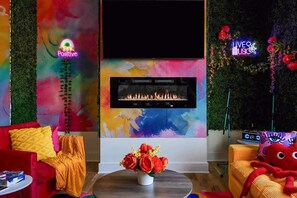 Ein modernes Wohnzimmer mit Kamin, lebhaftem abstrakten Wandbild und einer Neonreklame.