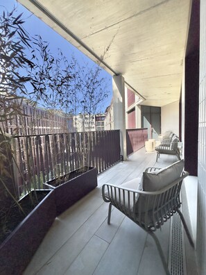 A balcony with a metal railing, a bench, and potted plants. - Bolhão Prime | Luxe 4BR + Garage (Porto)