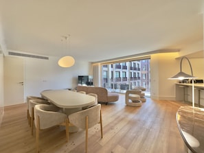 A modern living room with a dining area, a TV, and a large window with a city view. - Bolhão Prime | Luxe 3BR + Garage (Porto)