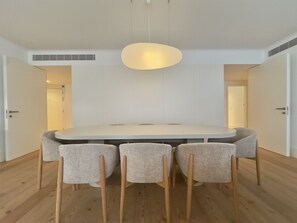 A modern dining area with a round table, four chairs, and a pendant light. - Bolhão Prime | Luxe 3BR + Garage (Porto)