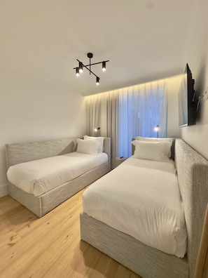 A hotel room with two beds, a modern chandelier, and a large window with curtains. - Bolhão Prime | Luxe 3BR + Garage (Porto)