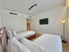 Una habitación de hotel moderna con dos camas, un televisor de pantalla plana y una lámpara de pie.