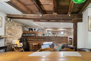 Un intérieur rustique avec une table à manger en bois, des chaises, un canapé et un mur en pierre.