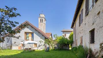 Ein Innenhof mit einem Gebäude, das einen Turm, eine überdachte Sitzgelegenheit und eine Rasenfläche aufweist.