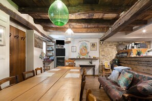 Ein rustikaler Essbereich mit Holztisch und -stühlen, einer Couch und einer Steinwand.