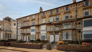 A row of terraced houses with brick facades, white windows, and a central staircase leading to the entrance. - Host & Stay | The Beach (Filey)