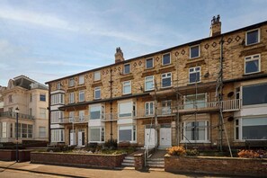 A row of terraced houses with brick facades, white windows, and a central staircase leading to the entrance. - Host & Stay | The Beach (Filey)