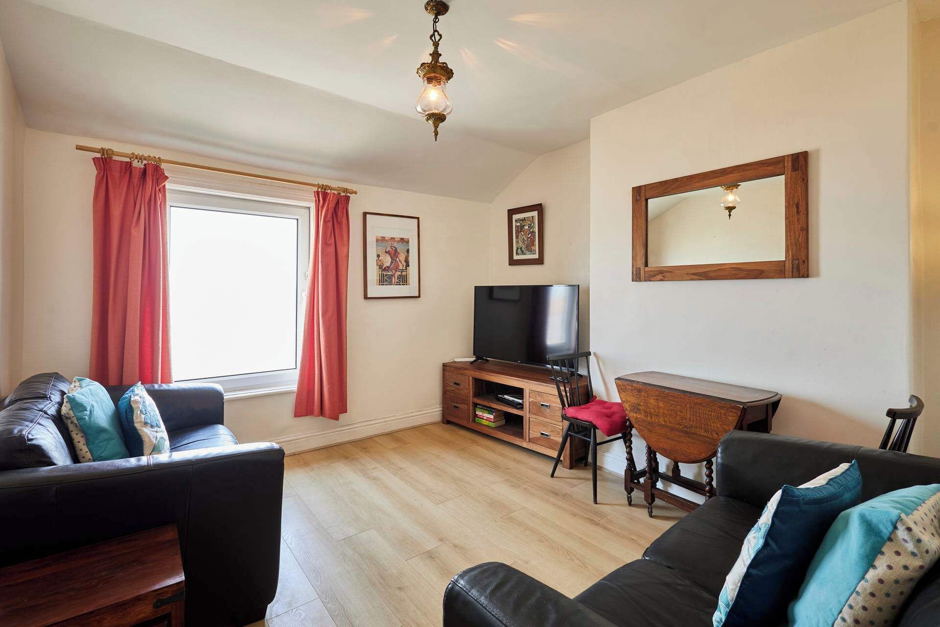 A living room with a sofa, a TV, a wooden cabinet, and a mirror.