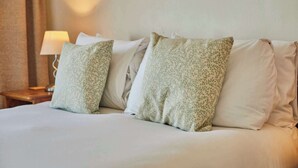 A neatly made bed with white linens and two pillows with a green leafy pattern. - Host & Stay | The Beach (Filey)
