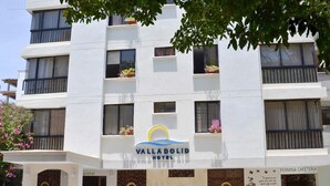 A multi-story hotel with balconies, a cafe, and outdoor seating. - HOTEL VALLADOLID (Santa Marta)