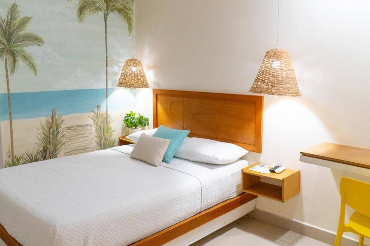 A bedroom with a bed, a nightstand, a desk, a chair, and a wall mural.