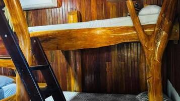Una cama litera con escalera, paredes de madera y una colcha estampada.