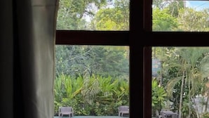 Una habitación con un ventanal grande, techo de madera y vista a un área de piscina exterior con vegetación.