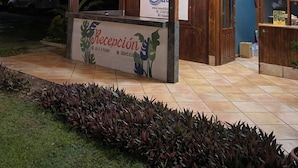 Un área de recepción con estructura de madera, un letrero y suelo de baldosas.