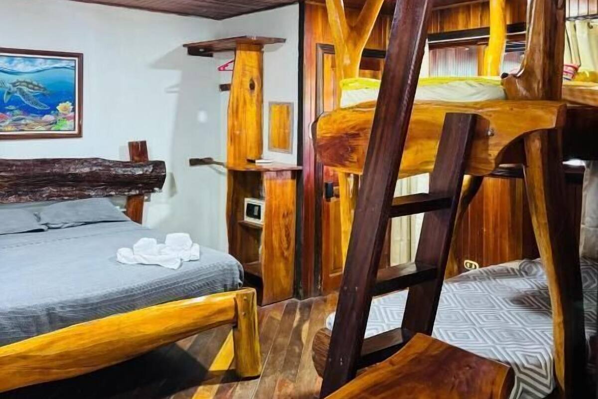 Una habitación rústica de madera con una litera, una cama individual y un cuadro en la pared.
