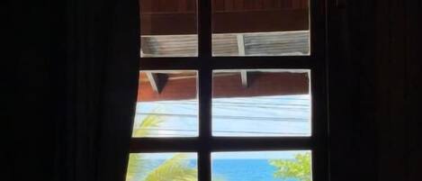 A window with a view of a beach and palm trees.